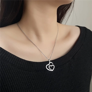 Detail of silver stainless steel hollow double heart pendant necklace on model