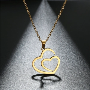 Detail of gold-plated stainless steel double hollow heart pendant under spotlight