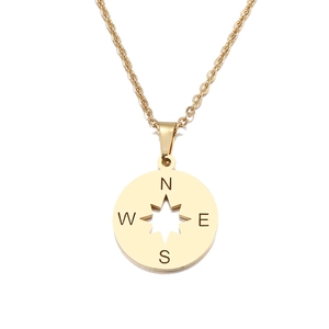 Détail d'un pendentif boussole doré avec gravure NESW et découpe en étoile
