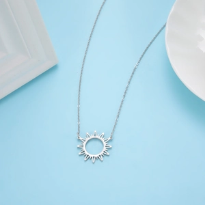 Mise à plat d'un collier avec pendentif soleil en acier inoxydable sur fond bleu