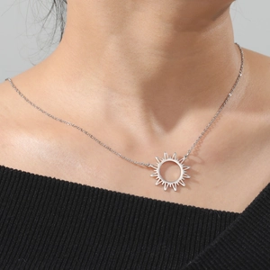 Gros plan d'un collier pendentif soleil minimaliste sur modèle avec rayons découpés