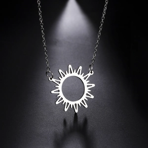 Vue macro d'un collier pendentif soleil argenté avec rayons géométriques sur fond sombre