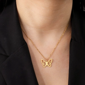 Collier minimaliste en or avec pendentif papillon porté par un mannequin en costume