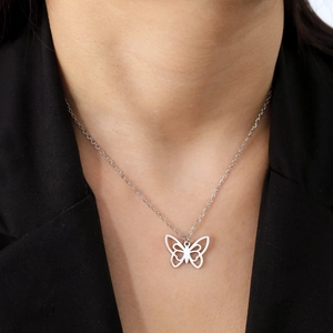 Détail macro du collier pendentif papillon évidé argenté porté par un modèle