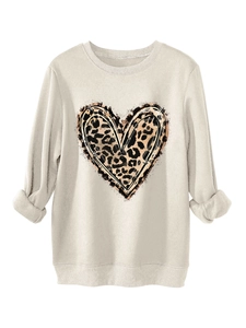 Detail of plush beige sweatshirt showing leopard print heart pattern and soft knit fabric