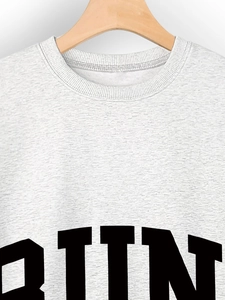 Close-up of heather grey crew neck sweatshirt featuring bold black RUN lettering print