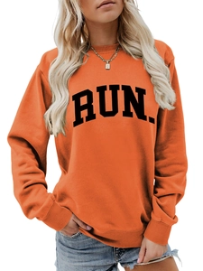 Close-up of orange sweatshirt showing black RUN. print and ribbed neckline detail