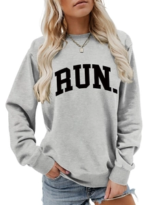Detail of grey crewneck sweatshirt featuring bold black RUN print and golden necklace accessory