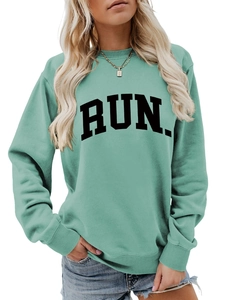 Close-up of mint green crewneck sweatshirt featuring bold black RUN letter printing