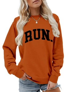Detail view of RUN letter print on casual orange crewneck sweatshirt with cotton texture