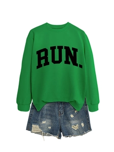Detail of green RUN sweatshirt with bold lettering paired with distressed denim shorts
