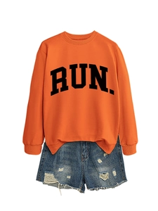 Detailed flat lay of orange crewneck sweatshirt with RUN text and distressed denim shorts