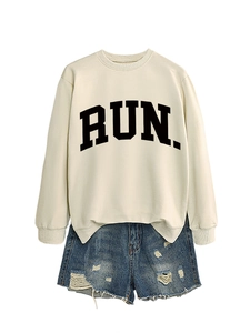 Flat lay of cream RUN sweatshirt paired with distressed blue denim shorts in vintage style