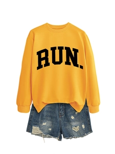 Flat lay of yellow long-sleeve sweatshirt with black RUN lettering and denim shorts