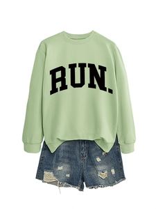 Close-up of light green sweatshirt with RUN letter print and distressed denim shorts