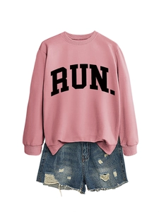 Close-up of pink crewneck sweatshirt with RUN text and distressed denim shorts