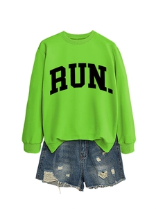 Detail of neon green crewneck sweatshirt with RUN text and distressed denim shorts