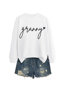 Flat lay of white granny heart sweatshirt paired with distressed blue denim shorts