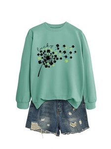 Dettaglio della felpa verde menta con stampa trifoglio e pantaloncini in denim