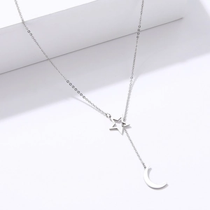 Collar de acero inoxidable plateado con colgantes de estrella hueca y luna en soporte blanco