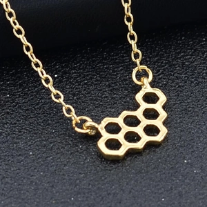 Vue macro d'un pendentif hexagonal doré en forme de nid d'abeille sur fond mat