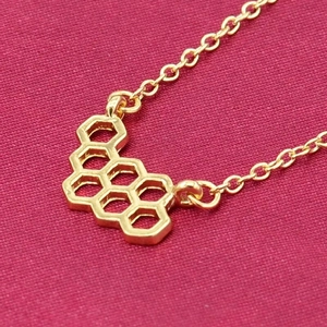 Gros plan détaillé d'un pendentif alvéolé hexagonal doré avec une chaîne à maillons fins