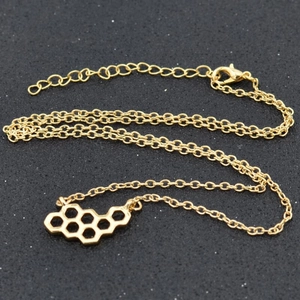 Détail du collier avec pendentif hexagone alvéolé doré et chaîne de réglage ajustable