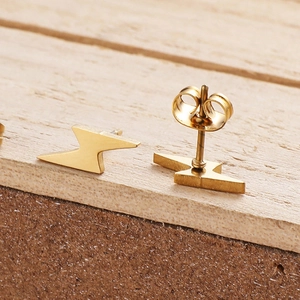 Polished gold lightning bolt earrings in stainless steel on a natural wood background