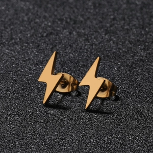 Macro shot of minimalist gold lightning bolt earrings on a black textured background