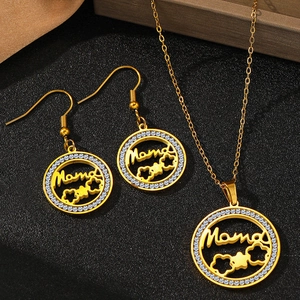 Détail macro du pendentif et des boucles d'oreilles Mama dorés avec cristaux blancs brillants