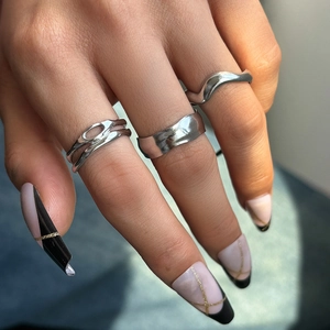 Set of three stackable silver rings in wavy, textured wide band, and hollow layered styles