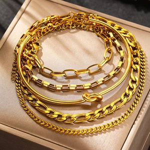 Dettaglio di un set di bracciali a catena dorata a strati con maglie cubane e graffetta