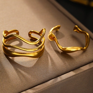 Detailed view of two gold oval chain-link rings with liquid metal texture on silk
