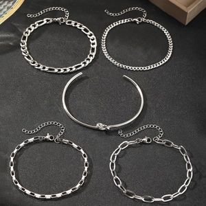 Vista dettagliata di un set di 5 bracciali a catena argento e polsino a nodo su nero