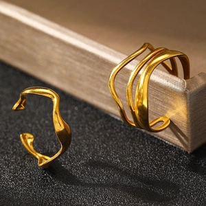 Close-up of matte gold geometric rings set with brushed texture and wavy chain design