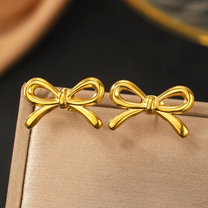Macro d'élégantes boucles d'oreilles nœud dorées 18K sur un coffret à bijoux satiné