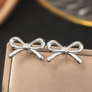 Vue macro de boucles d'oreilles nœuds en argent poli sur une boîte à bijoux dorée