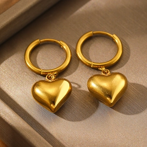 Boucles d'oreilles cœur plaqué or 18k polies sur un présentoir boîte à bijoux grise