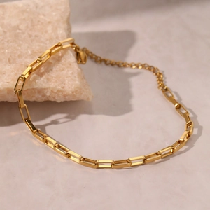 Bracelet chaîne trombone en acier inoxydable doré présenté sur une pierre naturelle