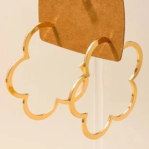 Dettaglio di grandi orecchini a cerchio dorati con design floreale traforato a 5 petali
