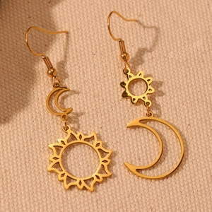 Macro view of gold sun and moon mismatched drop earrings on beige fabric background