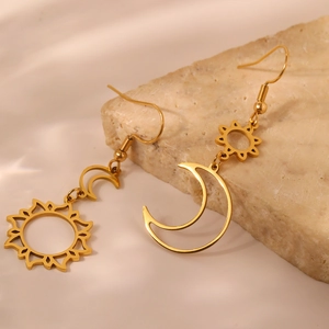 Detailed shot of golden sun and moon earrings on a textured stone display