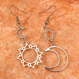 Bohemian silver sun and moon asymmetric earrings on a textured mineral stone background