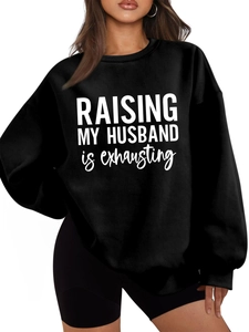 Close-up of oversized black sweatshirt featuring white RAISING MY HUSBAND slogan print