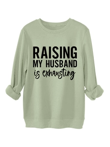 Close-up of olive green sweatshirt with Raising My Husband print and ribbed neckline