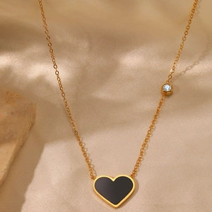 Minimalist punk heart necklace in black and gold finish on elegant silk background