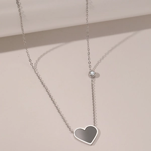 Detail of silver chain necklace featuring a black heart pendant and a clear round zircon