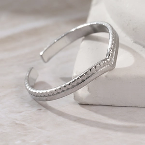 Minimalist silver V-shaped open ring with beaded edges on a white stone base