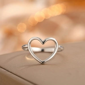 Macro shot of silver-colored hollow heart-shaped ring on champagne leather surface