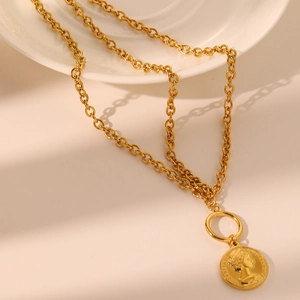 Détail d'un pendentif pièce d'or vintage avec relief sur une grosse chaîne à maillons
